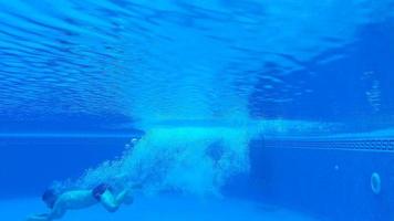 submarino disparo como un hombre inmersiones dentro el piscina y nada debajo el agua video