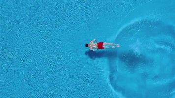 Aerial view of man in red shorts swims in the pool video