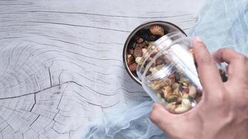 Top view of mixed nut in a bowl on wooden table video