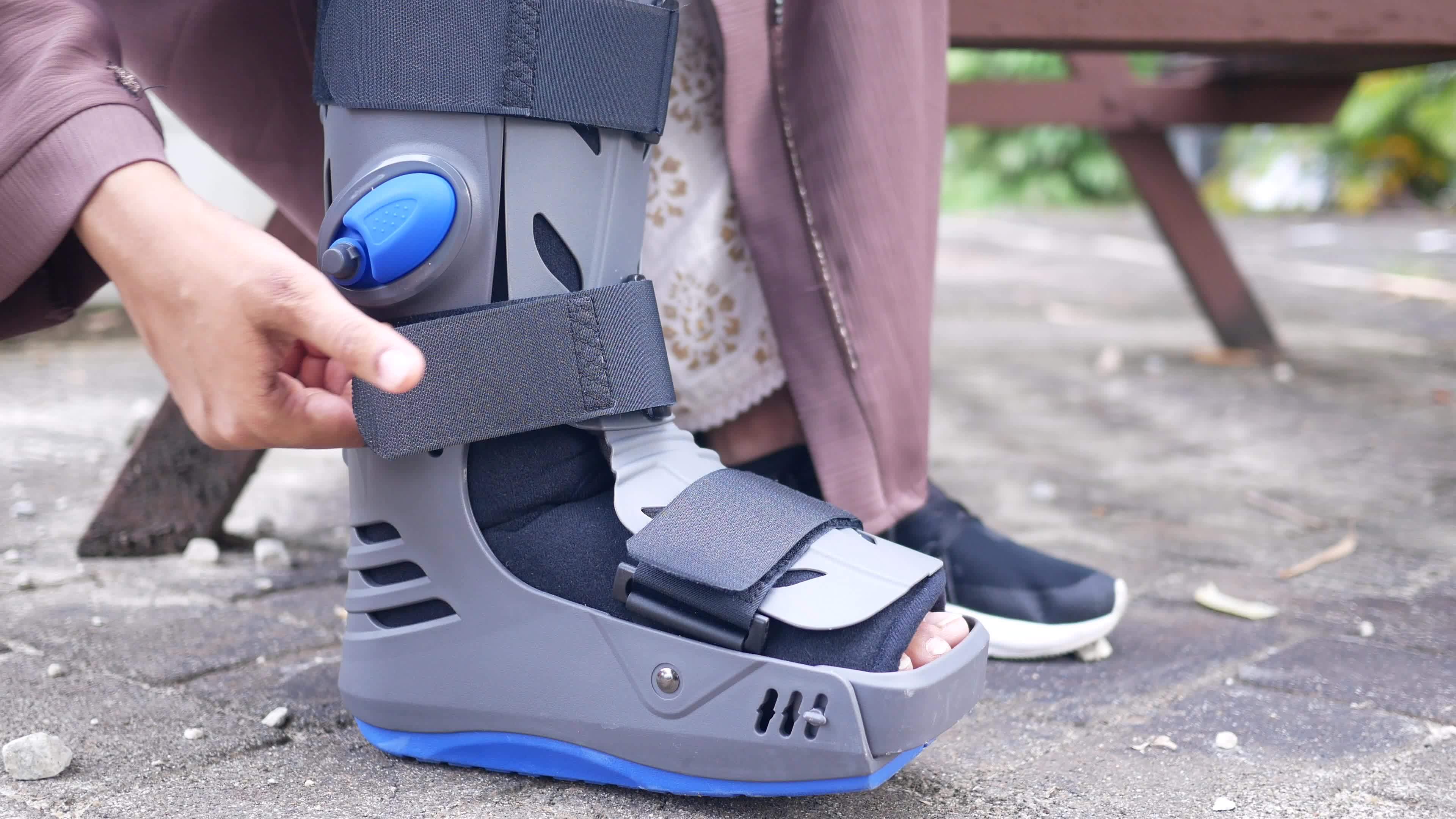 Woman broken feet with a grey plastic boot ankle brace injury