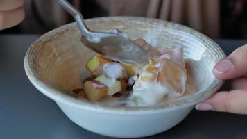 vers fruit gemengd met yoghurt in een kom Aan tafel video