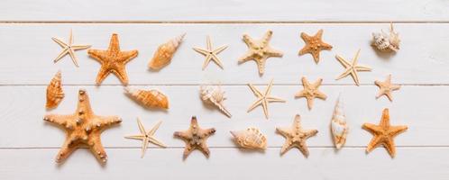 Top view of starfish and many seashells on white wood texture background top view. Copy space background, summer concept photo