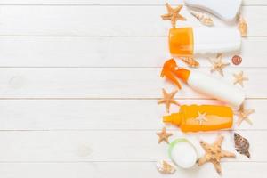 flat lay concept summer travel vacation. Sunscreen bottles with starfish on white wooden table with copy space photo