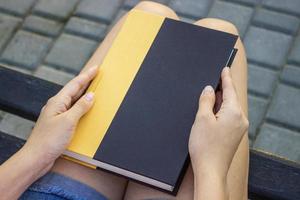 un joven mujer participación un libro en el parque. foto