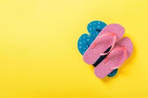 A lot of colored flip flops on yellowbackground. Top view with copy space photo