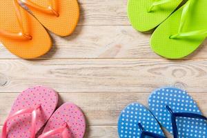 a lot of flip flop colored sandals, summer vacation on wooden background, copy space top view photo