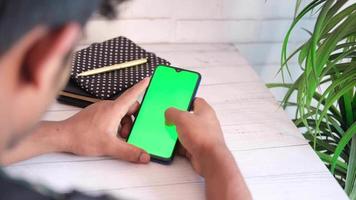 top view of man hand using smart phone display green screen video