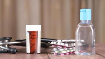 Hand sanitizer, stethoscope and pills container on wooden background video
