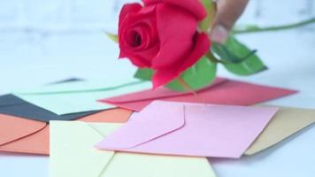 Red rose on many colorful envelope on table video