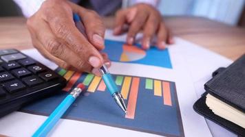 Mano de hombre con lápiz analizando gráfico de barras en papel video