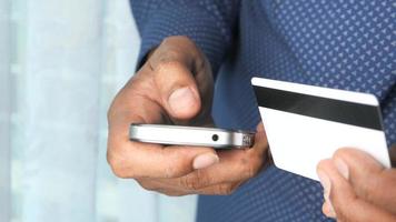 traseiro Visão do homem segurando crédito cartão e usando inteligente telefone compras conectados video