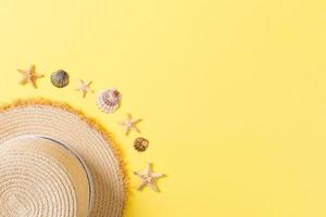 Beach hat with seashells on brown yellow table. summer background concept with copy space top view photo