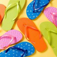 many colored flip flops on yellow background. Copy space top view photo