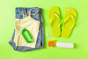 Flat lay composition with green Beach accessories on green color background. Summer holiday background. Vacation and travel items top view photo