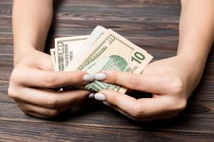 Perspective view of ten dollar banknotes in female hands on wooden background. Business and financial concept photo