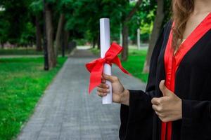 contento mujer en su graduación día universidad. educación y pulgares arriba mujer. foto