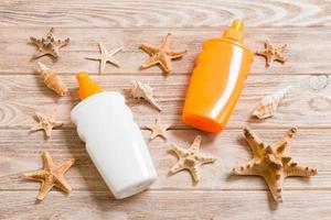 Top view of sunscreen bottle with seashells and starfish on wooden board background with copy space. flat lay concept of summer travel vacation photo