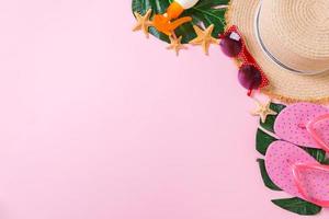 Beach accessories with straw hat, sunscreen bottle and seastar on pink background top view with copy space photo