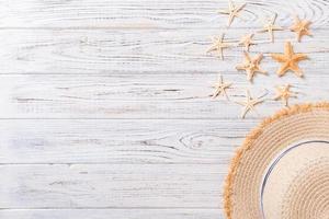 Summer holiday background with straw hat and seashells on wooden background top view with copy space photo