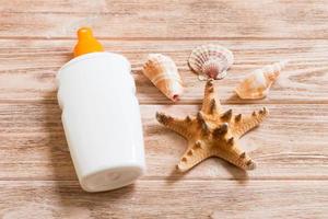 Sunscreen bottles with seashells and starfish on wooden table flat lay concept of summer travel vacation photo