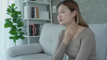 Aisa woman put her hand on her neck due to a sore throat. female tonsillitis causes a inflammation. treated by taking water, taking antibiotics, consult a doctor, virus, corona virus, Influenza, flu video