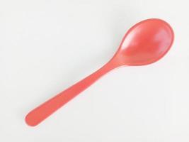 Red plastic spoon on white background photo