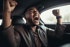A dark-skinned man with his hands up and joyful emotions on his face in the interior of the car. photo