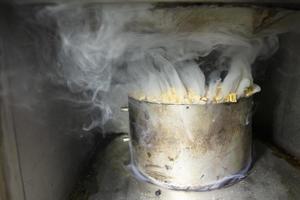 Metal pot with sawdust and smoke in an industrial oven for smoking fish. photo