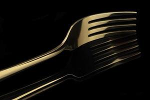 Gold fork on a black background with reflection. Cutlery. photo