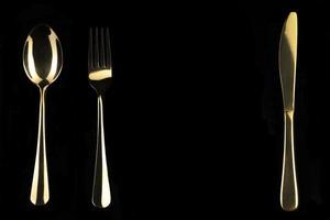oro cuchillo y cuchara en un negro antecedentes. cuchillería. foto