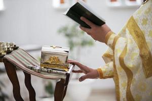 The hands of the priest hold the Bible against the background of the church. photo