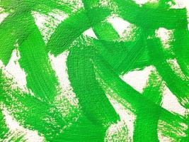 Large strokes of bright green paint on textured horizontal white canvas. Abstract acrylic, gouache or tempera green paint texture background. Selective focus, close up. photo