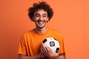 Cheerful young man holding soccer ball and looking at camera isolated over solid color background photo