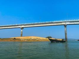 A boat is passing under a bridge that has a bridge on it. Bridge over the sea. photo