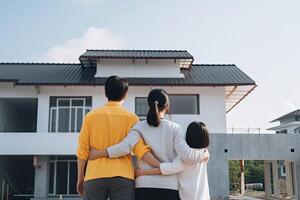 Happy family stands in front of their new home. photo