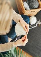 Young woman knitting warm scarf indoors photo