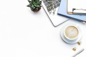 Modern white office desk table with laptop, notebook and other supplies. photo