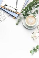 Modern white office desk table with laptop, notebook and other supplies. photo