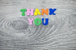 Closeup shot of colorful text thank you on gray wooden background photo