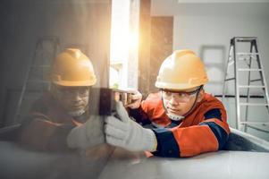 Asian worker using a level gauge to measure wall masonry working with wall concrete blocks.Engineer doing a level check on the wall at construction site photo