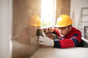 asiático trabajador utilizando un nivel calibre a medida pared albañilería trabajando con pared hormigón bloques.ingeniero haciendo un nivel cheque en el pared a construcción sitio foto