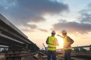 asiático arquitecto y maduro supervisores reunión a construcción sitio multiétnico trabajadores y ingenieros que se discute planes dos construcción trabajadores trabajando juntos mientras visitando Autopista construcción foto