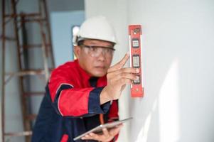 a construction worker or architect wearing a hard hat is checking the wall with a level gauge. photo