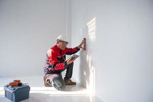 a construction worker or architect wearing a hard hat is checking the wall with a level gauge. photo