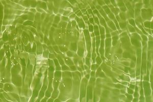 Light green water with ripples on the surface. Defocus blurred transparent colored clear calm water surface texture with splashes and bubbles. Water waves with shining pattern texture background. photo