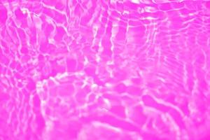 púrpura agua con ondas en el superficie. desenfocar borroso transparente rosado de colores claro calma agua superficie textura con chapoteo y burbuja. agua olas con brillante modelo textura antecedentes textura foto