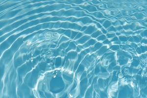 Blue water with ripples on the surface. Defocus blurred transparent blue colored clear calm water surface texture with splashes and bubbles. Water waves with shining pattern texture background texture photo