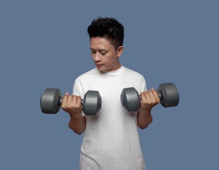 Handsome man doing exercises using dumbbells isolated on plain background photo