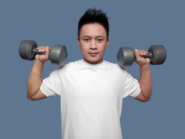 Young man doing the movement of lifting or biceps curl with dumbbells in both hands photo