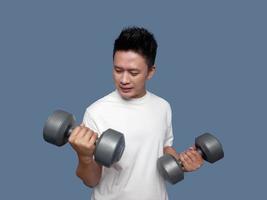 Young man doing arm exercises using dumbbells isolated on plain background photo